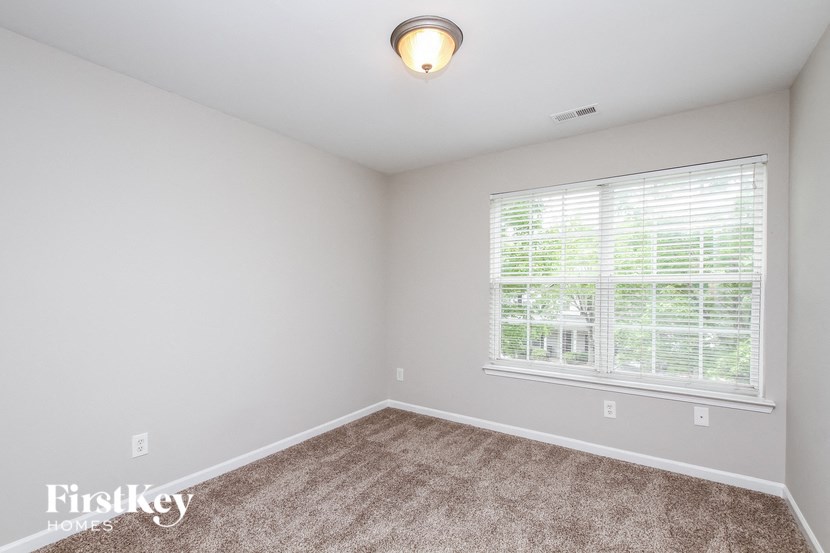 the second bedroom is spacious and has carpeted floors and a large window