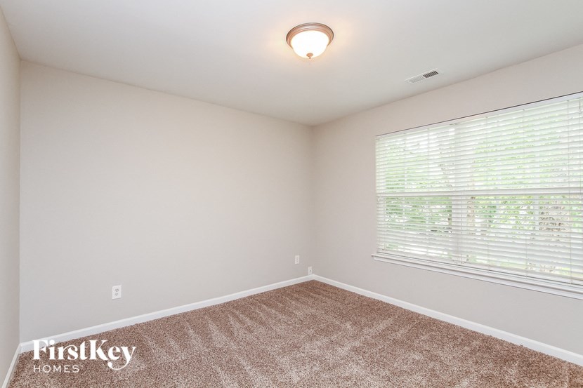 the spacious living room has a large window and carpeted flooring