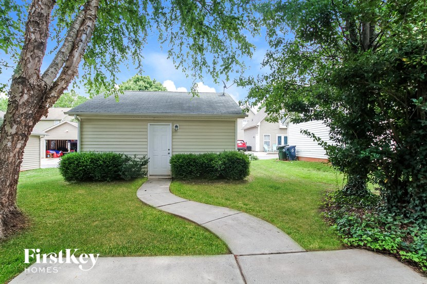 a small yellow house with a sidewalk in front of it