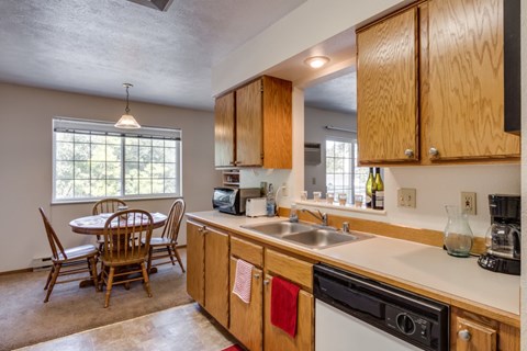A kitchen with wooden cabinets and a dining table with chairs.