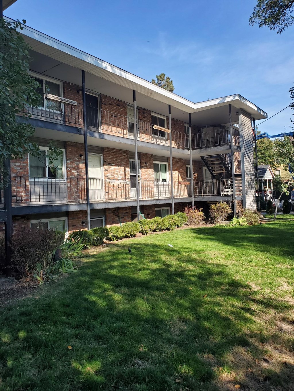 the front of a building with a green yard and a balcony