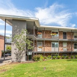 a large brick apartment building with a green lawn