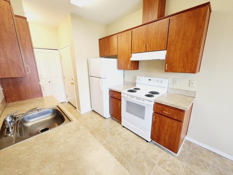 A kitchen with white appliances and wooden cabinets.