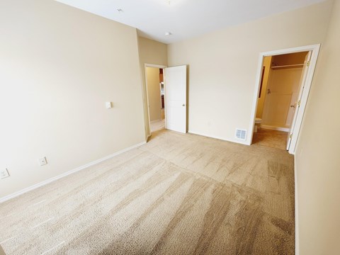 A room with carpeted floor and two open doors.