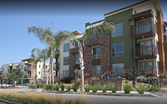 an image of an apartment building with palm trees in front of it