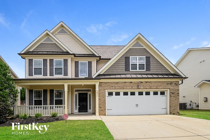a home with a white garage door in front of a brick house