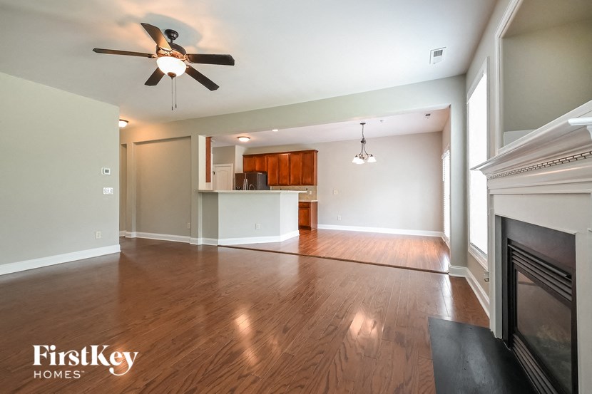 an empty living room with a fireplace and a ceiling fan