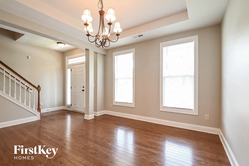 an empty living room with wood floors and a chandelier