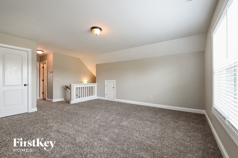 a large carpeted room with a white door and a window
