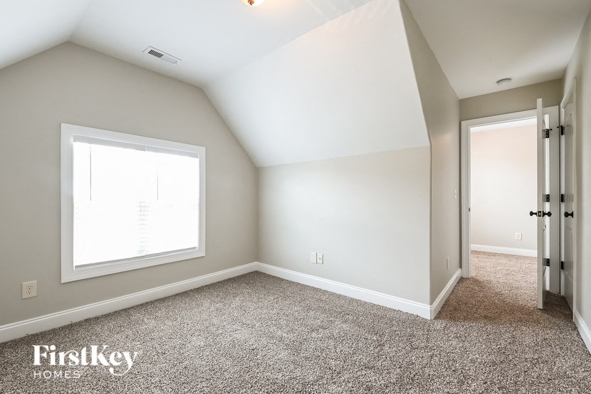 a bedroom with white walls and carpet and a window