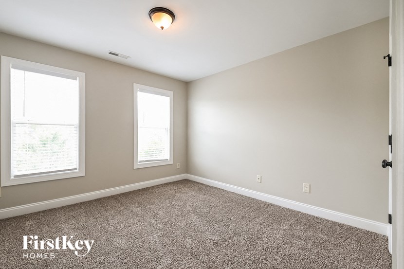 an empty room with carpet and two windows