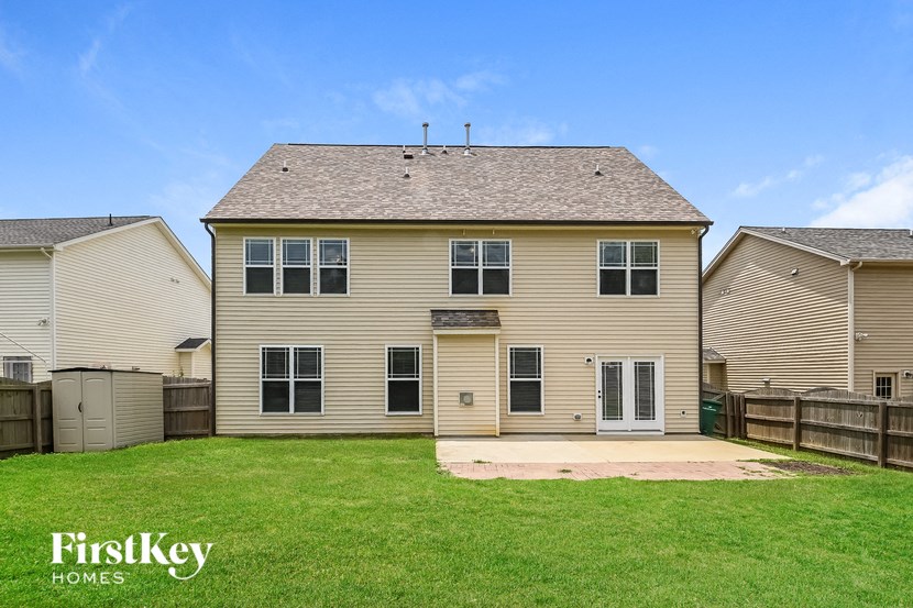 a yellow house with a backyard and a green lawn