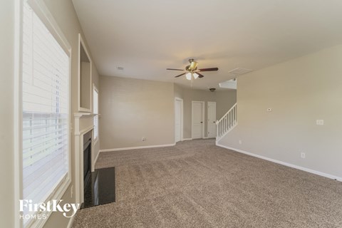 a spacious living room with carpet and a ceiling fan