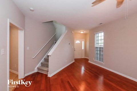 A spacious room with wooden floors and a staircase leading to the upper level.