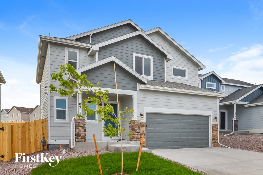 a blue house with a wooden fence and a driveway