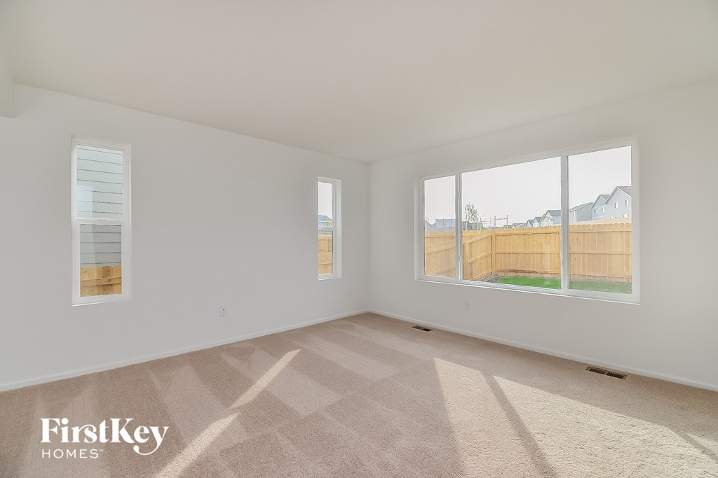 a spacious living room with two large windows and a wooden fence