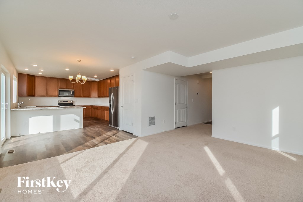 an empty living room and kitchen with white walls and wood cabinets