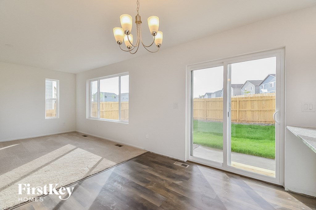 an empty living room with sliding glass doors to a backyard