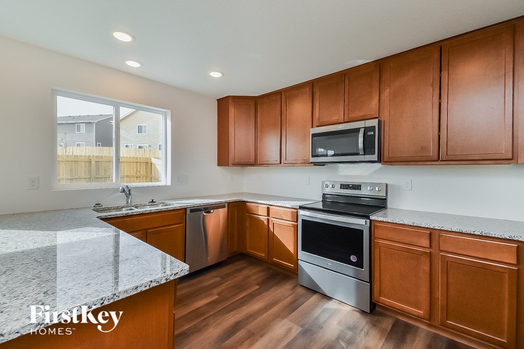 a kitchen with wooden cabinets and granite counter tops and stainless steel appliances