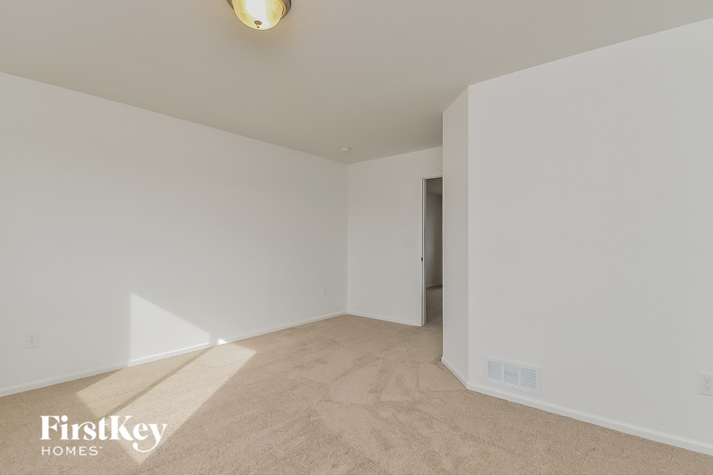 a spacious living room with white walls and flooring and a door to a hallway