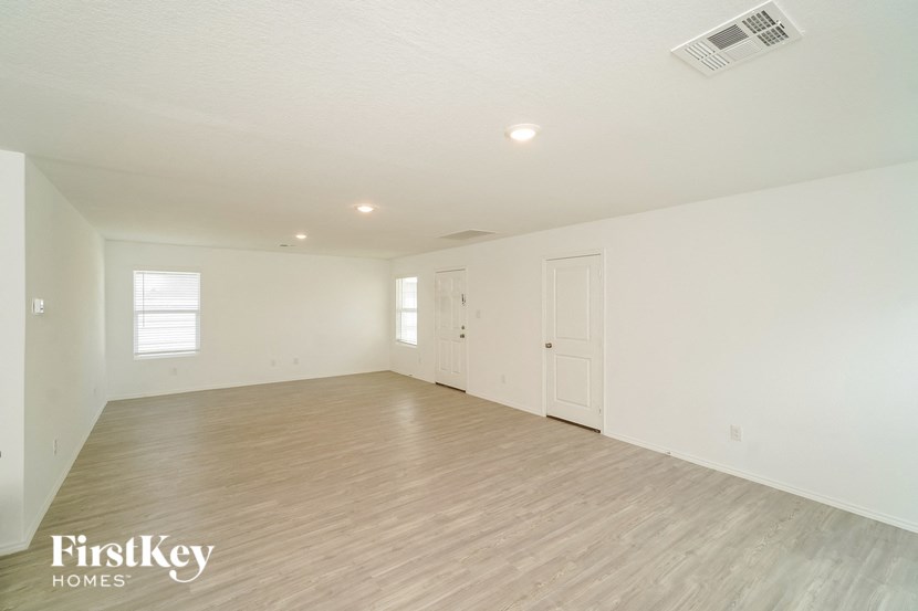 a spacious living room with white walls and wood flooring