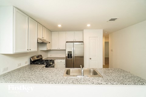 a kitchen with white cabinets and a sink and a refrigerator