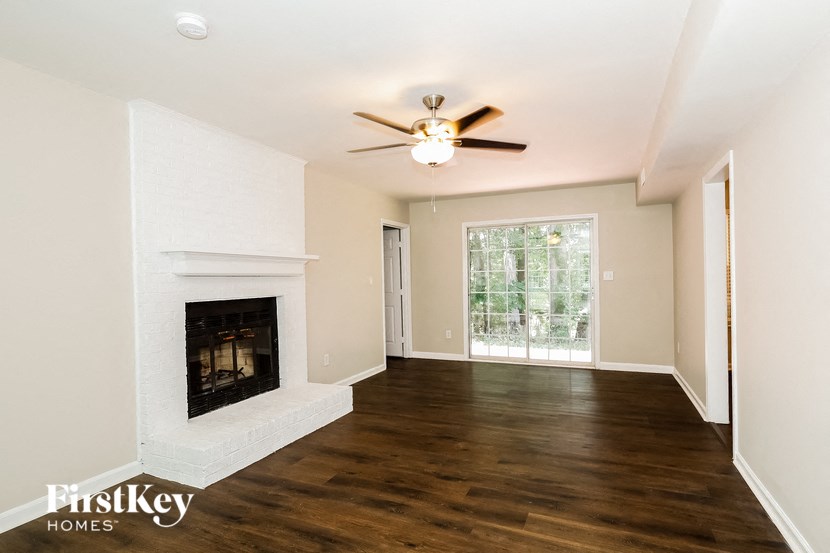 A spacious living room with a fireplace and a ceiling fan.