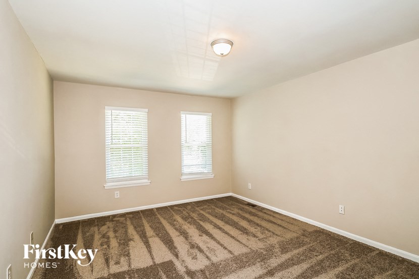 A room with a carpeted floor and two windows.