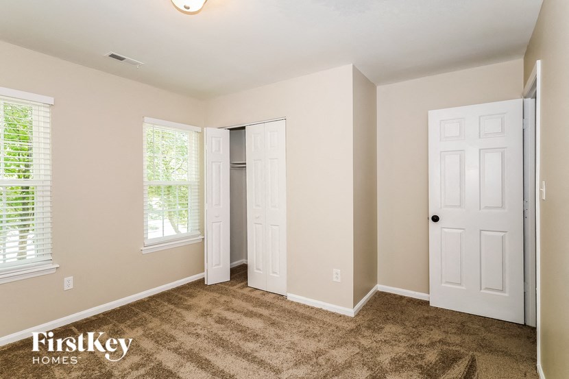 A room with a carpeted floor and two doors.