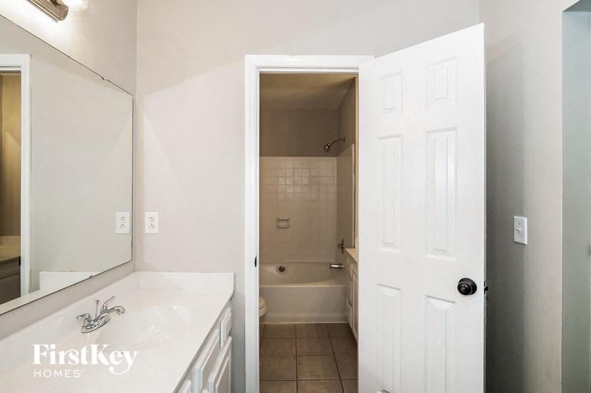 A white bathroom with a white door and a white sink.