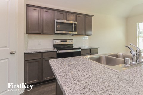 A kitchen with a granite countertop and a stove top oven.