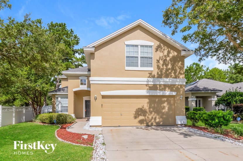A beige house with a garage door and a window is for sale.