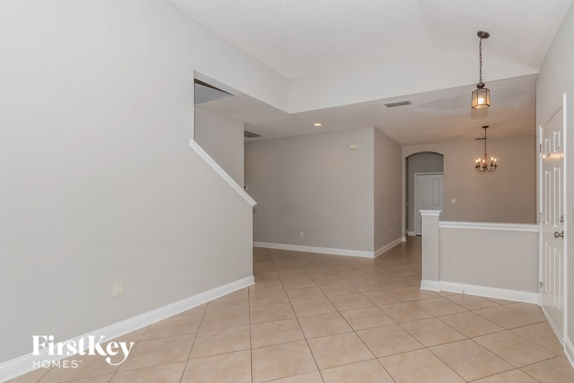 A spacious room with a staircase and a chandelier.