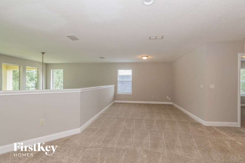 A spacious room with a carpeted floor and a large window.