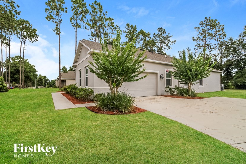A house with a driveway and a tree in front of it.