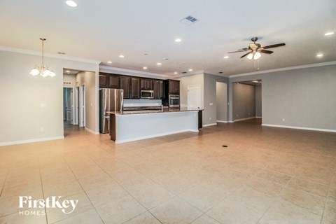 A spacious kitchen and living room with a ceiling fan and recessed lighting.