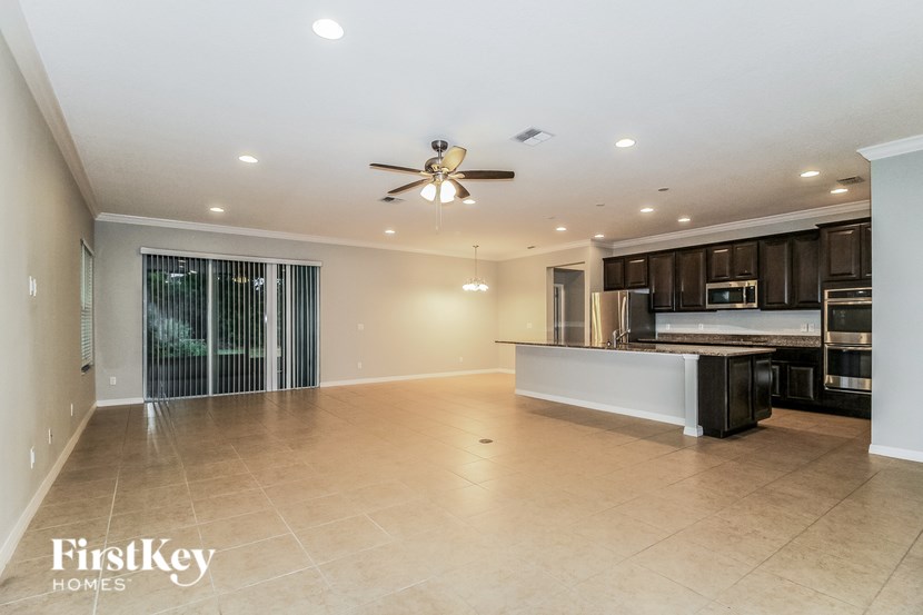 A spacious kitchen and living room with a ceiling fan and modern appliances.
