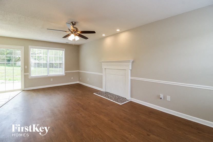 an empty living room with a ceiling fan and a window