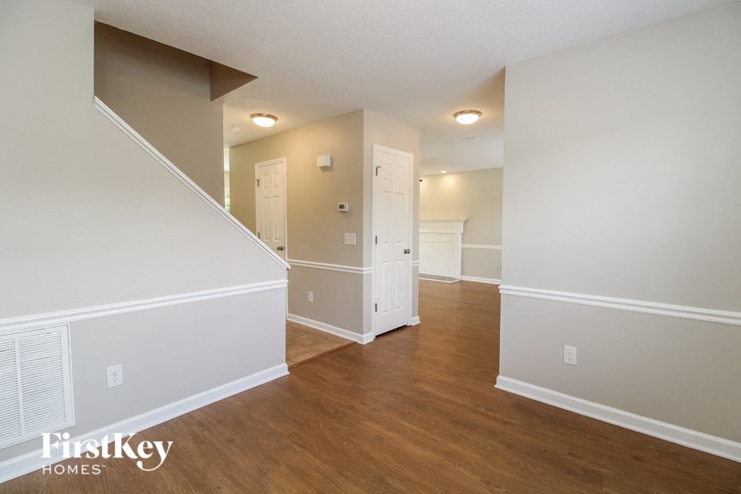 a renovated living room and dining room with white walls and wood flooring