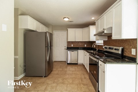a kitchen with white cabinets and a stainless steel refrigerator