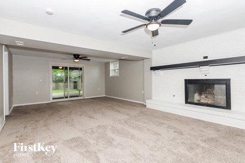 an empty living room with a fireplace and a ceiling fan