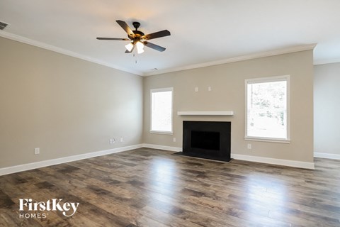A spacious living room with a fireplace and a ceiling fan.
