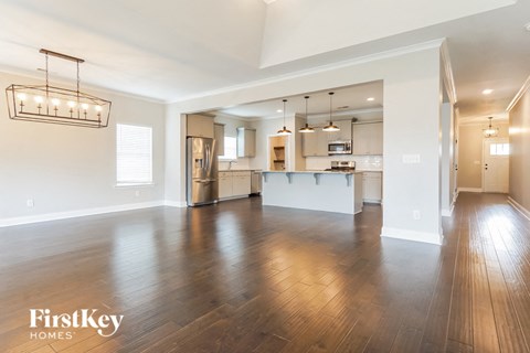 A spacious living room with wooden floors and a large mirror on the wall.