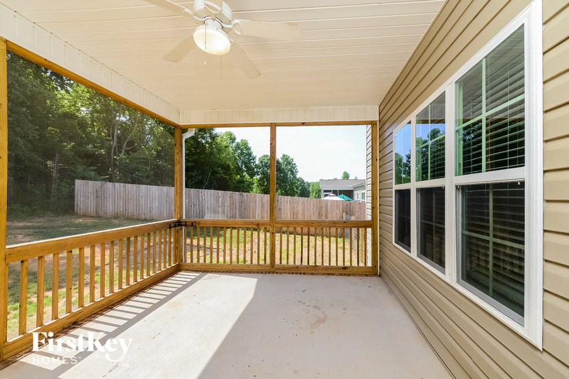 a covered porch with a view of a yard and a wood fence