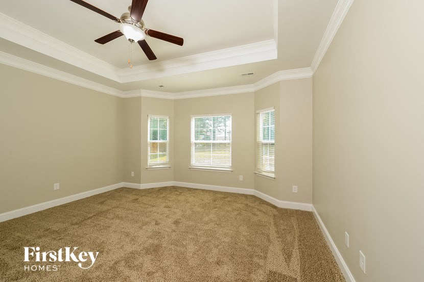 a empty living room with a ceiling fan and three windows