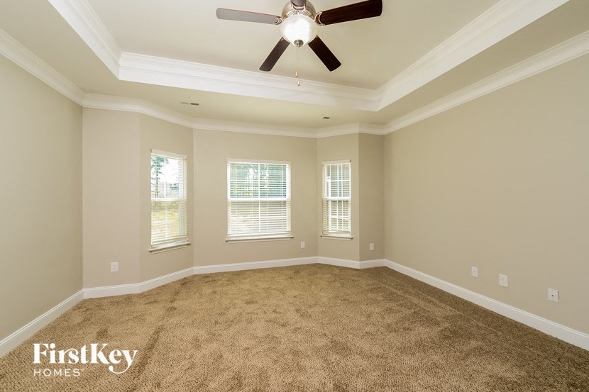 a empty living room with a ceiling fan and windows