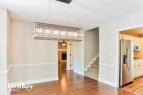 a kitchen and living room with a refrigerator and a chandelier