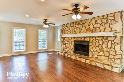 a living room with a stone fireplace and a wooden floor