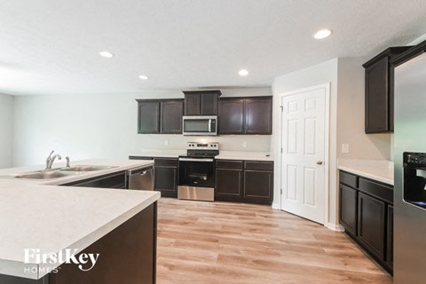 A kitchen with dark brown cabinets and a white door.