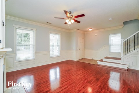 A spacious room with a wooden floor and a ceiling fan.